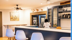 A modern bar area with a counter, bar stools, and a person behind the bar. - Kabakwe Guest Lodge (Victoria Falls)