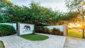 A paved entrance area with a sign featuring an elephant and the word "KABAKWE". - Kabakwe Guest Lodge (Victoria Falls)