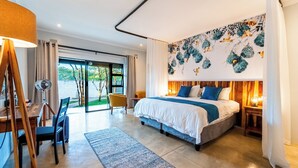 A modern hotel room with a large bed, a desk with a chair, a standing lamp, and a view of the outdoors. - Kabakwe Guest Lodge (Victoria Falls)