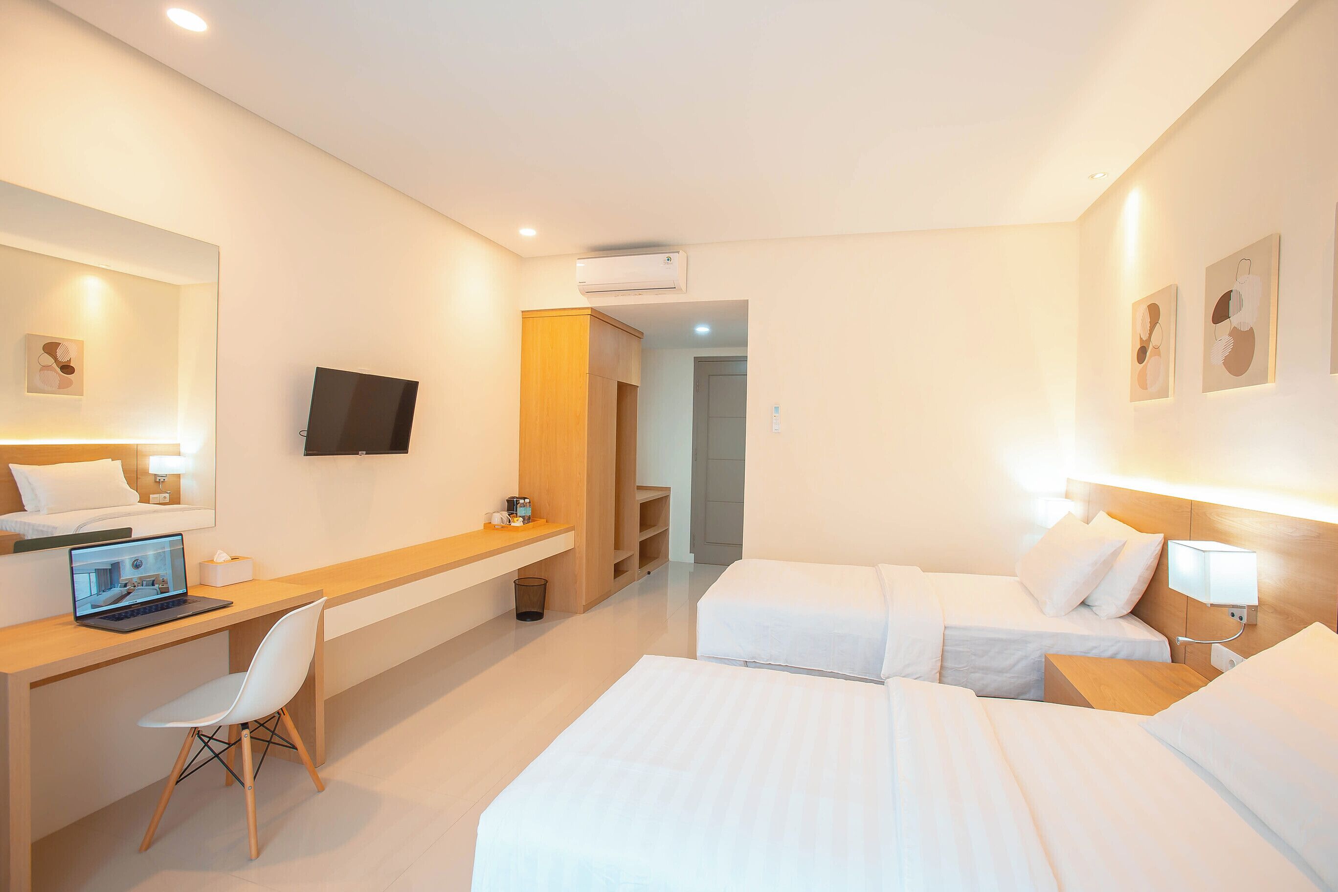 Ein Hotelzimmer mit Schreibtisch, zwei Betten, einem Fernseher und einem Spiegel.