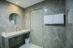 Une salle de bain moderne avec un mur en marbre, un lavabo, un miroir et un porte-serviettes.