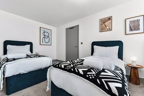 Een slaapkamer met twee bedden, een deur en lijstwerken aan de wanden.