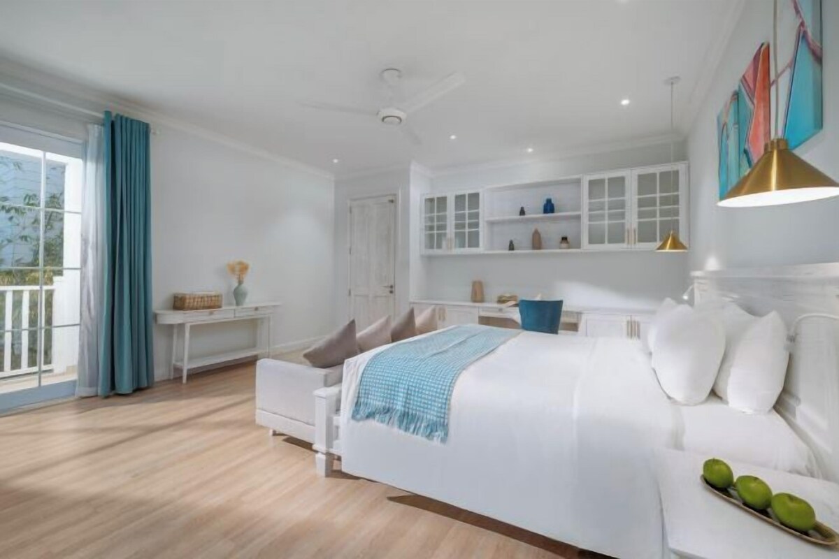 Un dormitorio moderno con una cama grande, una mesita de noche, un aparador y un ventanal con cortinas.