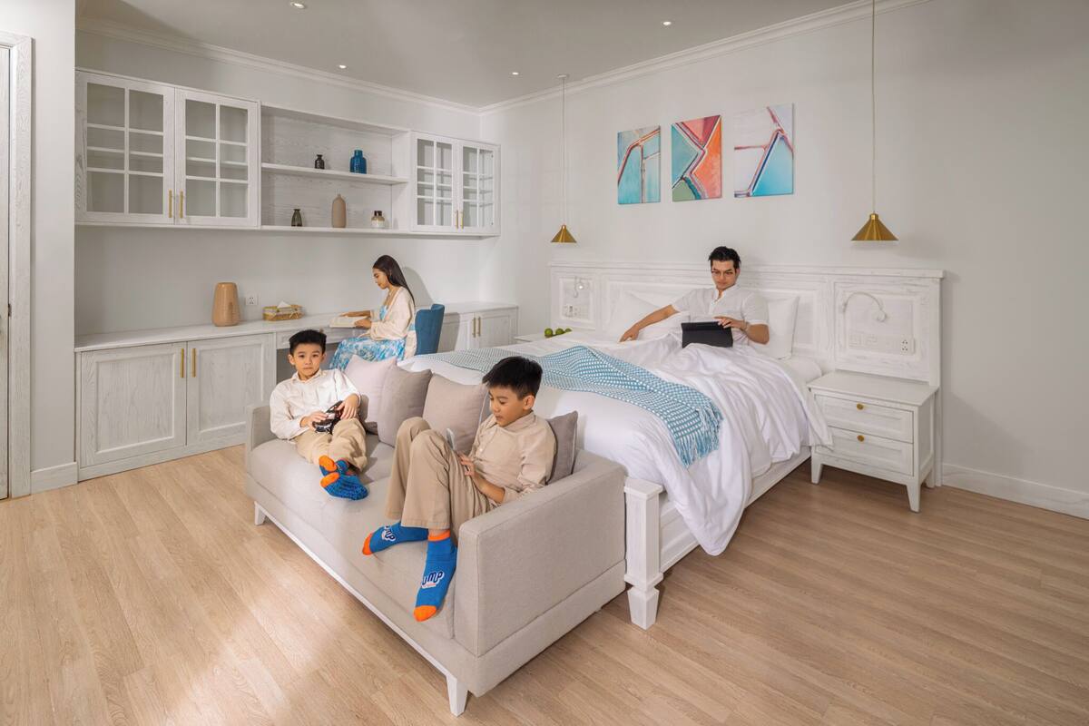 Une chambre moderne avec un lit, un canapé et une table de chevet. On y trouve également des armoires et une étagère avec des objets décoratifs.