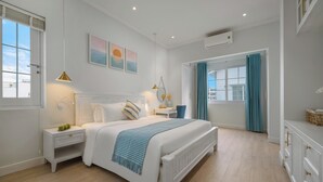 Een slaapkamer met een groot bed, nachtkastjes, een kast en een raam met gordijnen.
