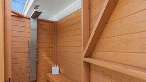 Una sauna de madera con un cabezal de ducha, un banco y dos botellas de champú.