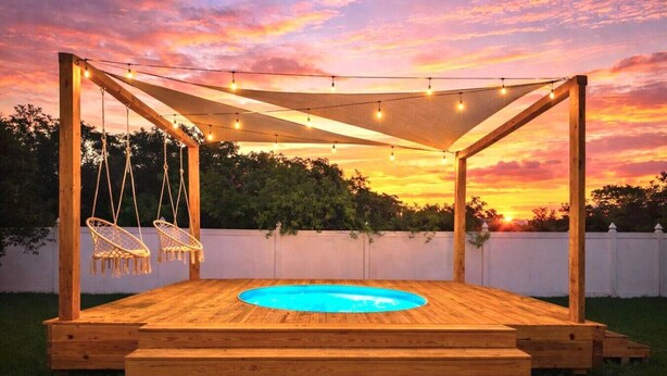 Terraza de madera con piscina, sillas colgantes y luces de cuerda.