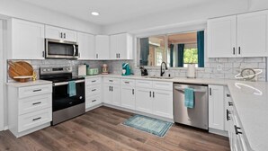 Una cocina moderna con armarios blancos, electrodomésticos de acero inoxidable y piso de madera.