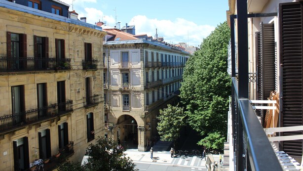 A view of a street with buildings, a tree, and a pedestrian crossing. - Pension Joakina (San Sebastián)