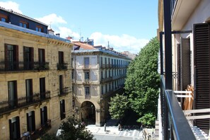 A view of a street with buildings, a tree, and a pedestrian crossing. - Pension Joakina (San Sebastián)