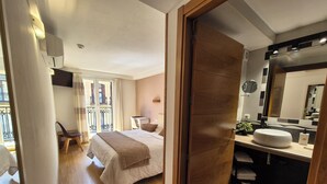 A hotel room with a bed, bedside table, and a bathroom with a sink and mirror. - Pension Joakina (San Sebastián)