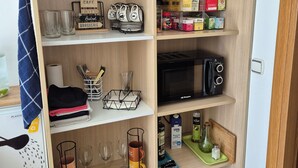 A well-organized kitchen with shelves containing kitchenware, a microwave, and various food items. - Pension Joakina (San Sebastián)