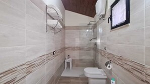 Une salle de bain équipée d’une douche, de toilettes et d’un porte-serviettes.