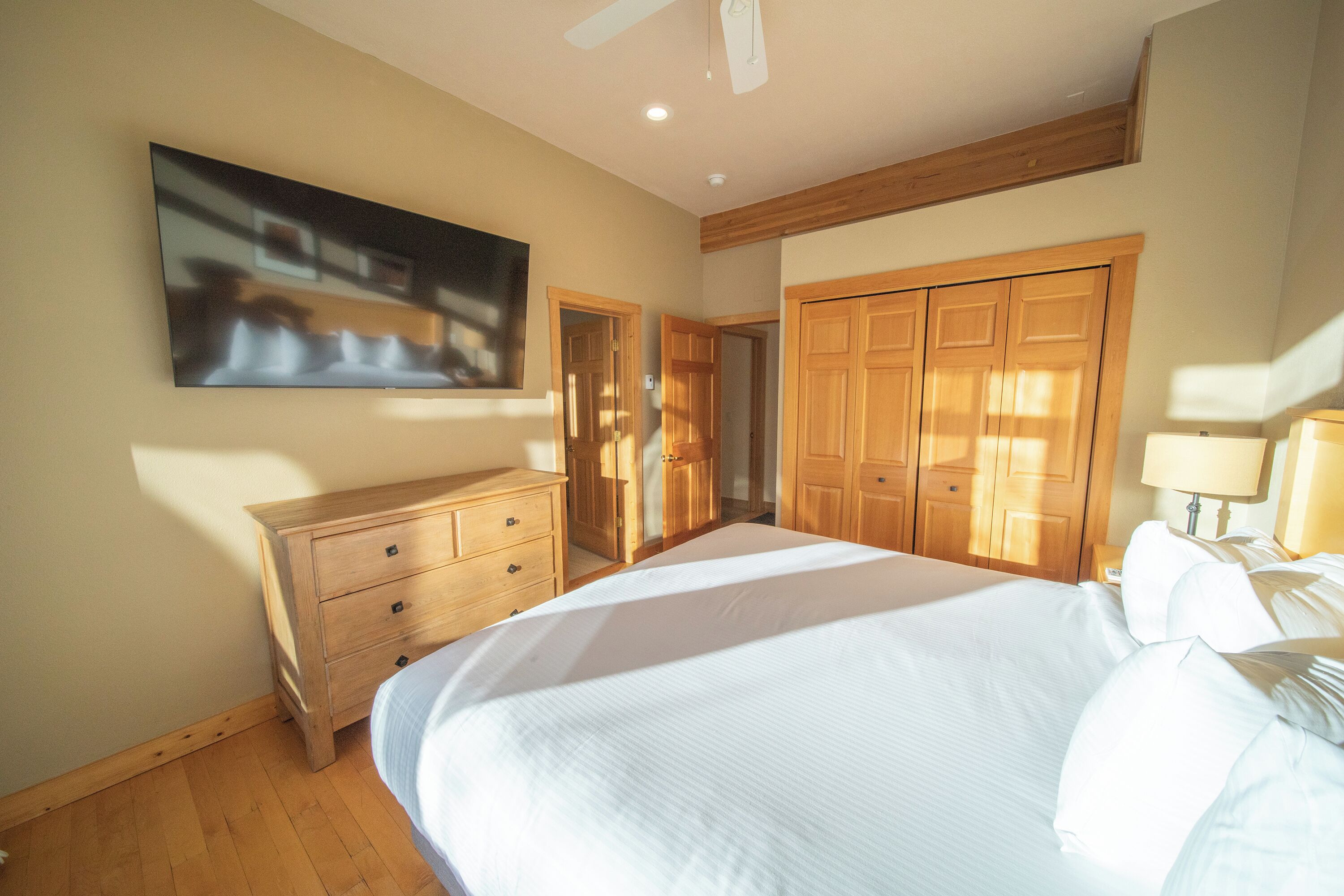 Camera da letto con un ampio letto, un armadio in legno e una televisione montata a parete.