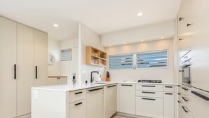 A modern kitchen with white cabinetry, a central island, and a built-in oven. - 1 Bedroom Suite with Breathtaking Ocean Views! Waikiki Shore 1210 (HONOLULU)