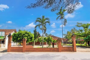 Zona residencial privada con muros de ladrillo, palmeras y un cielo azul despejado.