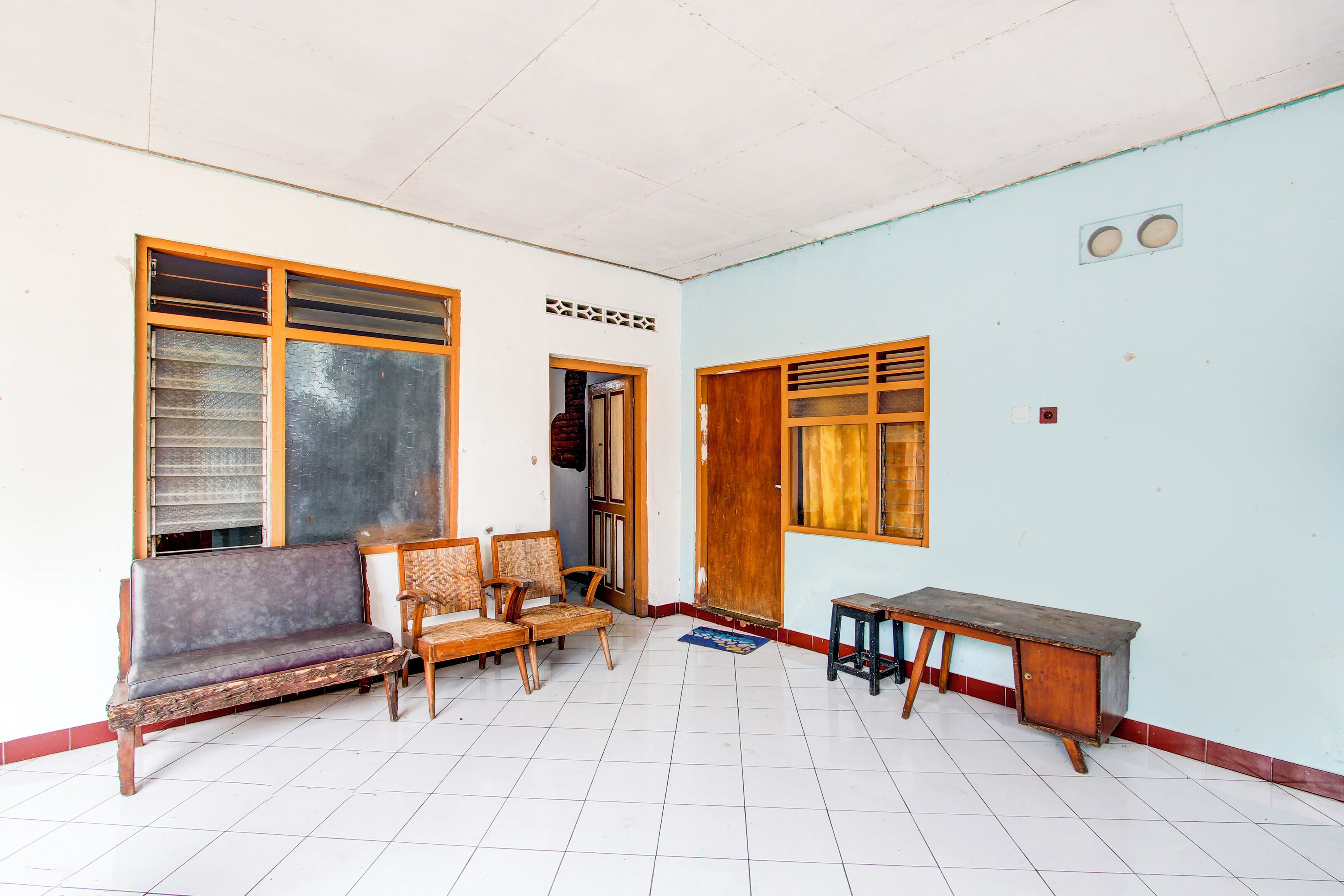 A room with a sofa, chairs, a desk, and a door.