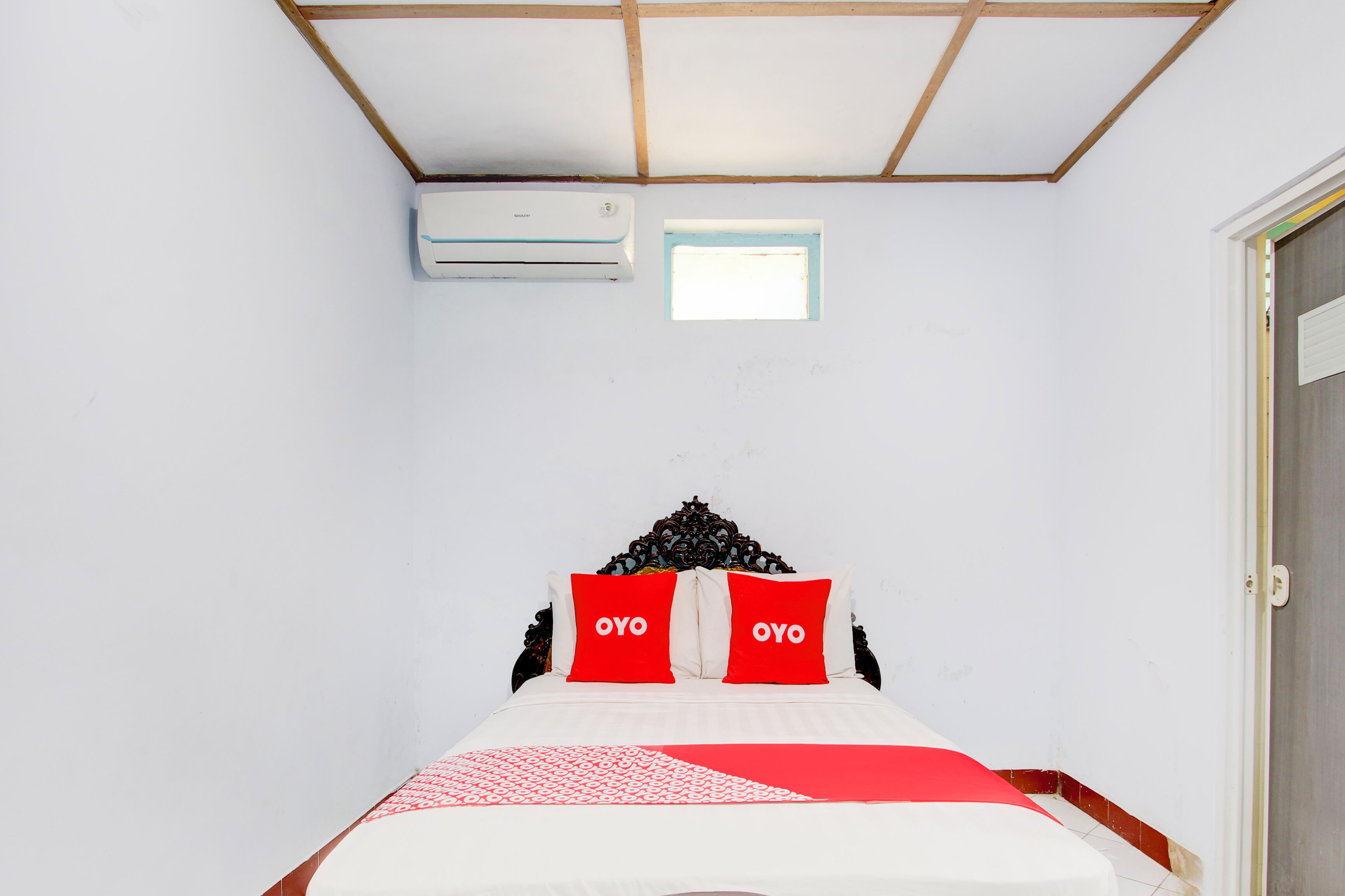 A bedroom with a bed, a window, and an air conditioning unit.