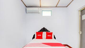 A bedroom with a bed, a window, and an air conditioning unit.