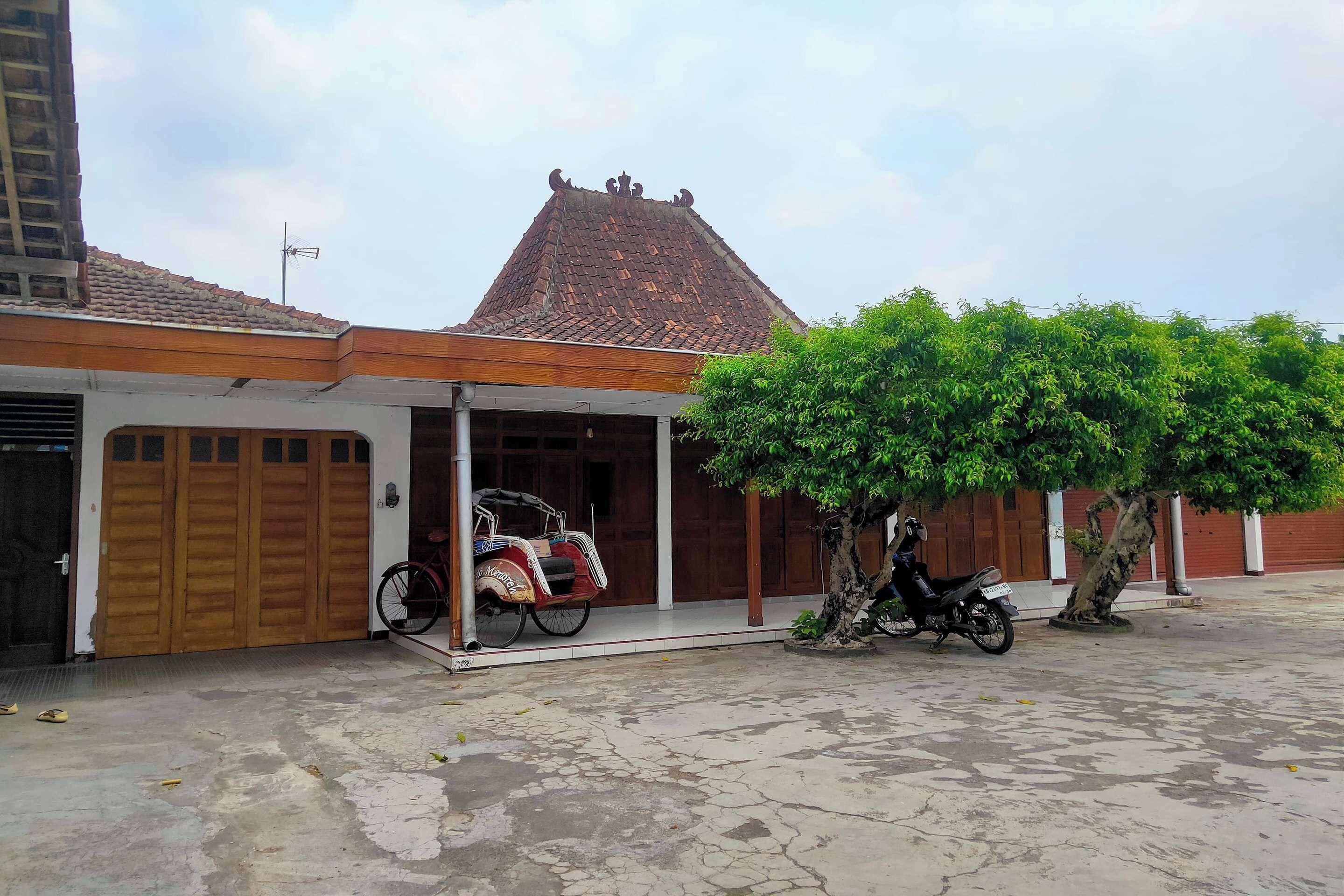 A building with a tiled roof, a covered porch, and a tree in front.