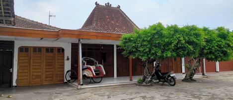 A building with a tiled roof, a covered porch, and a tree in front.