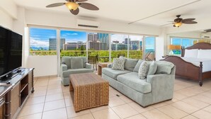 Un salón amplio con un televisor grande, asientos cómodos y un balcón con vistas a la ciudad.