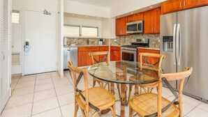Una cocina moderna con armarios de madera, electrodomésticos de acero inoxidable y una mesa de comedor de vidrio con sillas de mimbre.