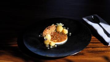 Un plato negro con un postre sobre una mesa de madera.