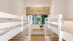 Cozy retreat with a bunk bed arrangement, a window overlooking lush greenery, and a small table with a vase of flowers.