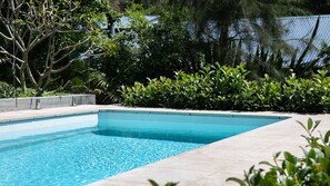 Relax by the pool surrounded by lush greenery and an outdoor space.