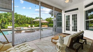 Une vaste terrasse dotée d’une piscine, de mobilier d’extérieur et offrant une vue sur une végétation luxuriante.