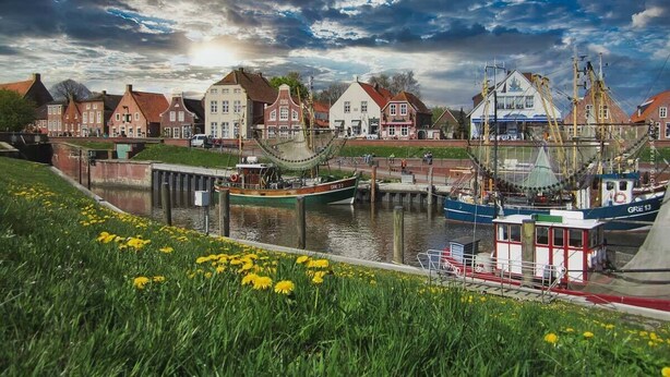 A canal with boats, a dock, and traditional buildings along the water. - Hafen Apartments  (Aurich)