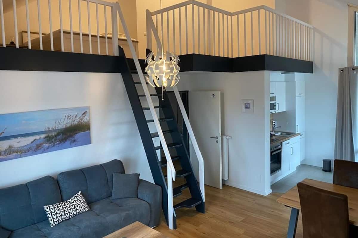A modern interior with a staircase connecting two levels, a dining area, and a kitchen.