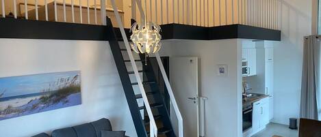Un interior moderno con una escalera que une dos niveles, un comedor y una cocina.