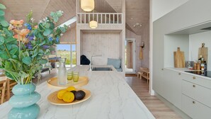 Une cuisine moderne dotée d’un plan de travail en marbre, de meubles en bois et d’un luminaire suspendu.