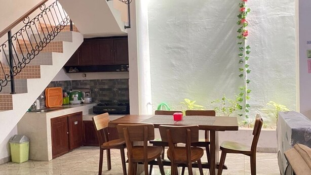 A modern kitchen with a dining area, a staircase, and a view of the outdoors. - ZG Home Solo (Surakarta)