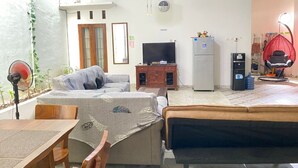 A living room with a sofa, a TV, a refrigerator, and a dining area with a table and chairs. - ZG Home Solo (Surakarta)
