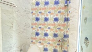 A bathroom with a toilet, shower, and floral-patterned wall. - ZG Home Solo (Surakarta)