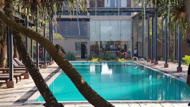 Une piscine à l’eau cristalline, entourée de palmiers et bordée d’une architecture moderne.