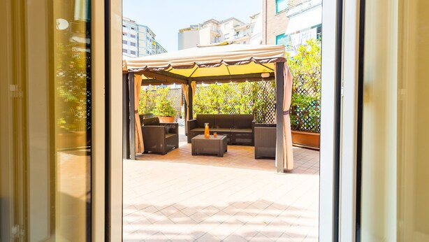 An outdoor patio area with a covered seating arrangement, a fire pit, and potted plants. - Partenope Spacious Home (Naples)