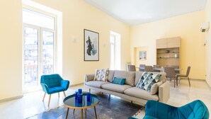 A modern living room with a sofa, two armchairs, a coffee table, and a dining area with chairs and a table. - Partenope Spacious Home (Naples)