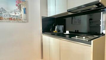 A modern kitchen with white cabinets, a black countertop, and a stainless steel range hood.