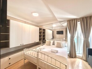 A bedroom with a bed, a wardrobe, a TV, and a window with curtains. - Apartmani Terminal (Budva)