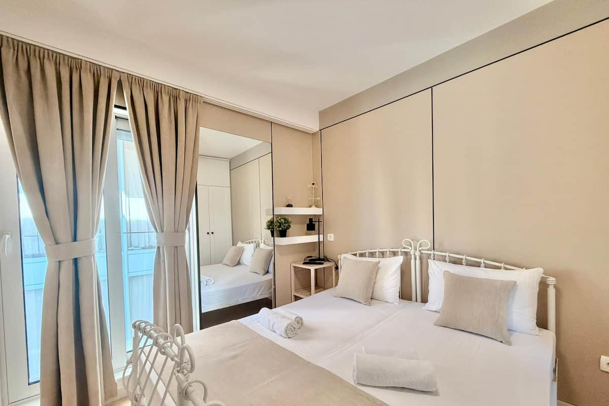 A hotel room with a large bed, a bedside table, a mirror, and a view of the outdoors.