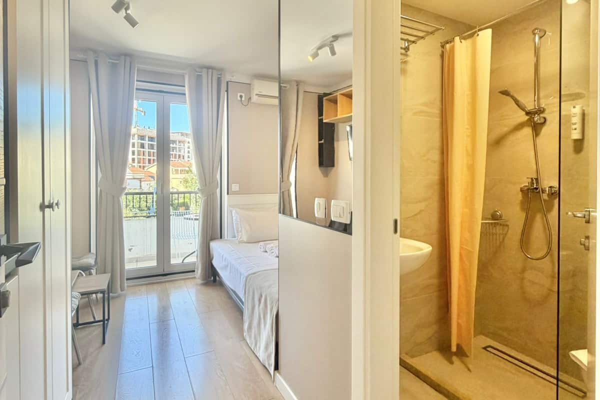 A hotel room with a balcony, a shower, and a bed.
