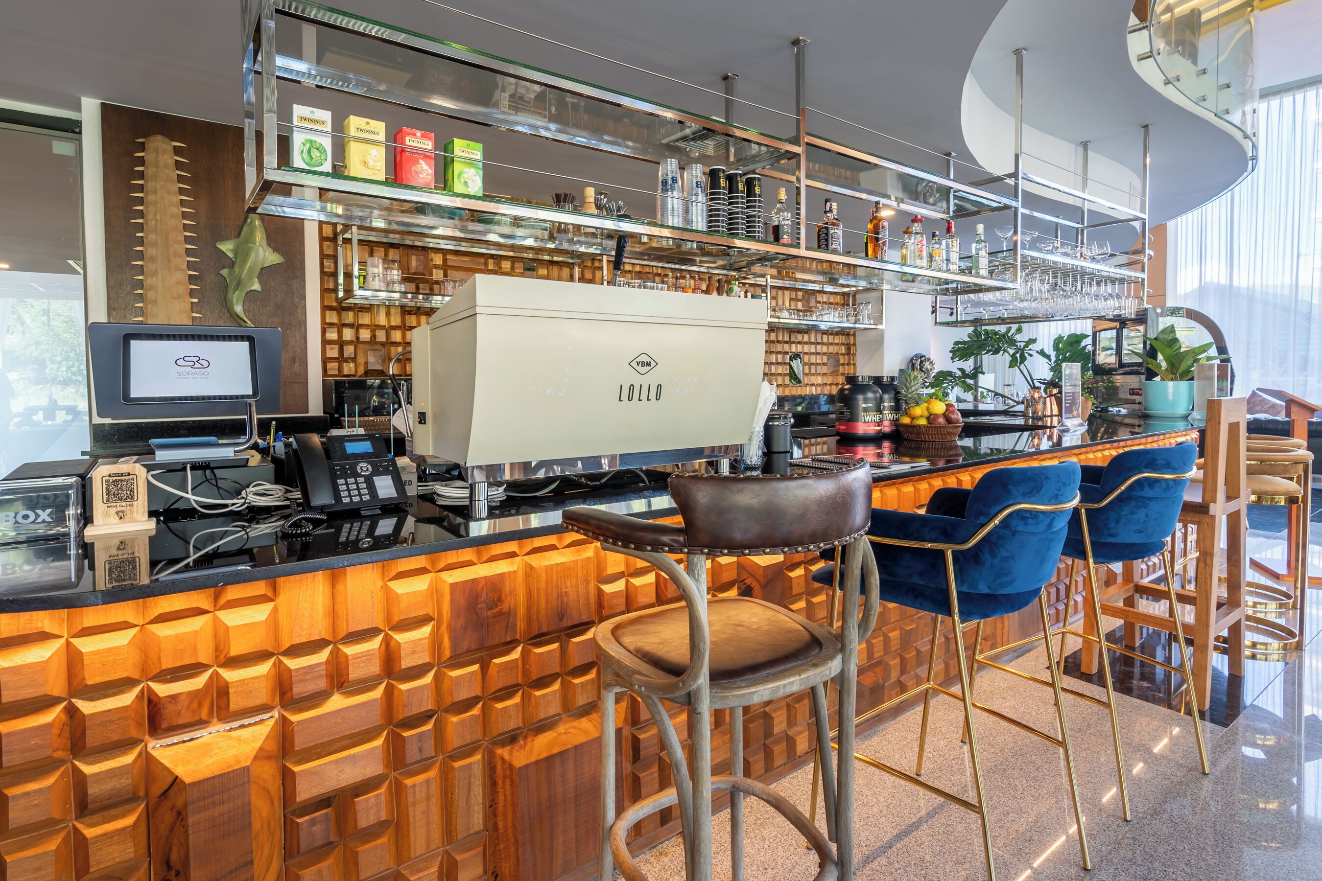 A modern bar area with a wooden bar counter, bar stools, and a coffee machine.