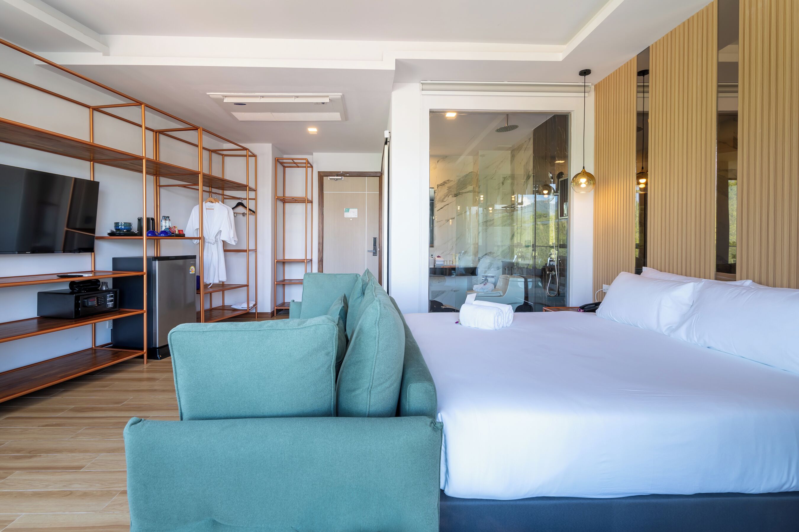 Een moderne hotelkamer met een groot bed, een groene fauteuil, een televisie en een houten plank.