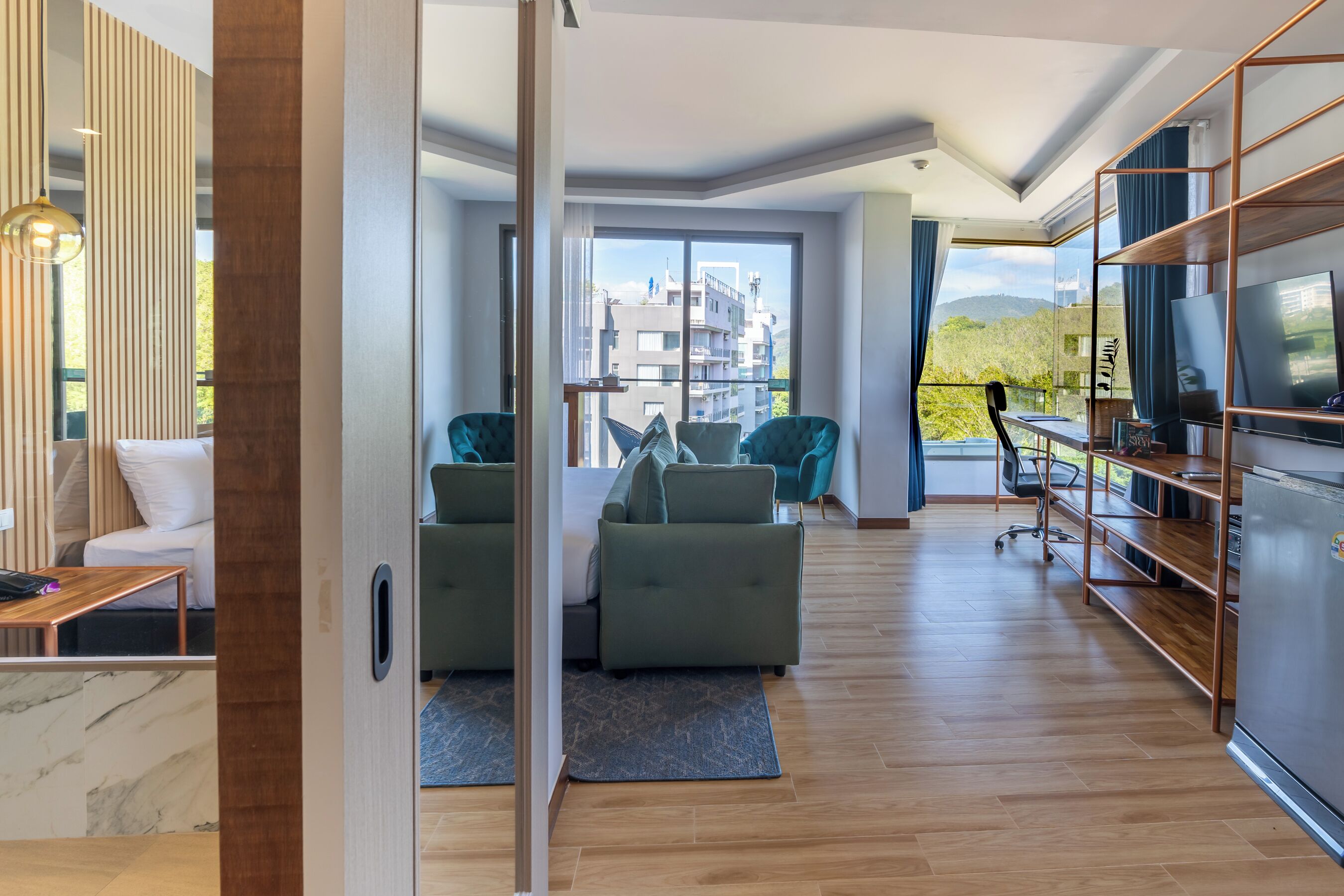 A modern living room with a sofa set, a TV, and a balcony with a city view.