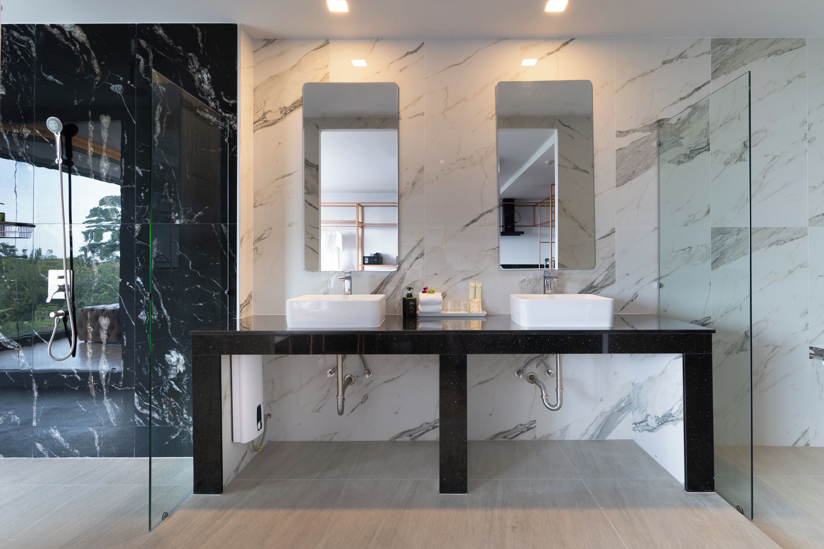 Ein modernes Badezimmer mit zwei Waschbecken, einer Duschkabine aus Glas und Marmorwänden.
