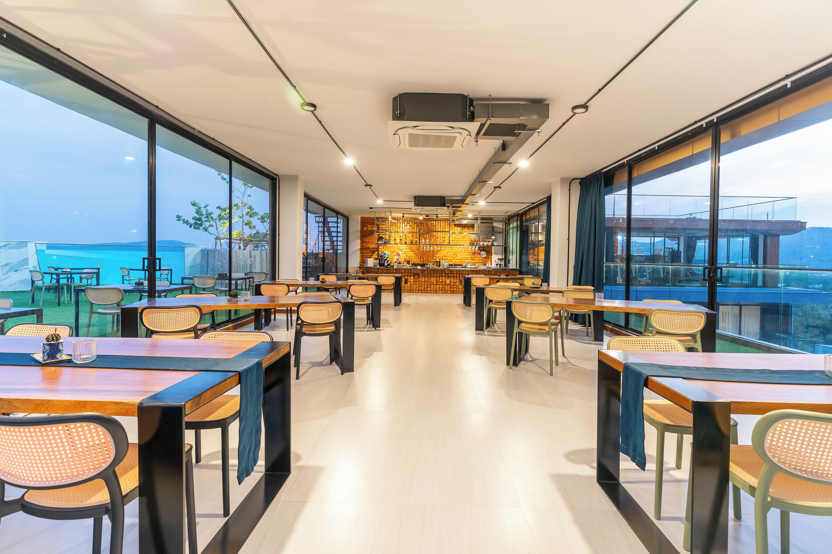 Un restaurant moderne avec de hauts plafonds, de grandes fenêtres et un bar central.